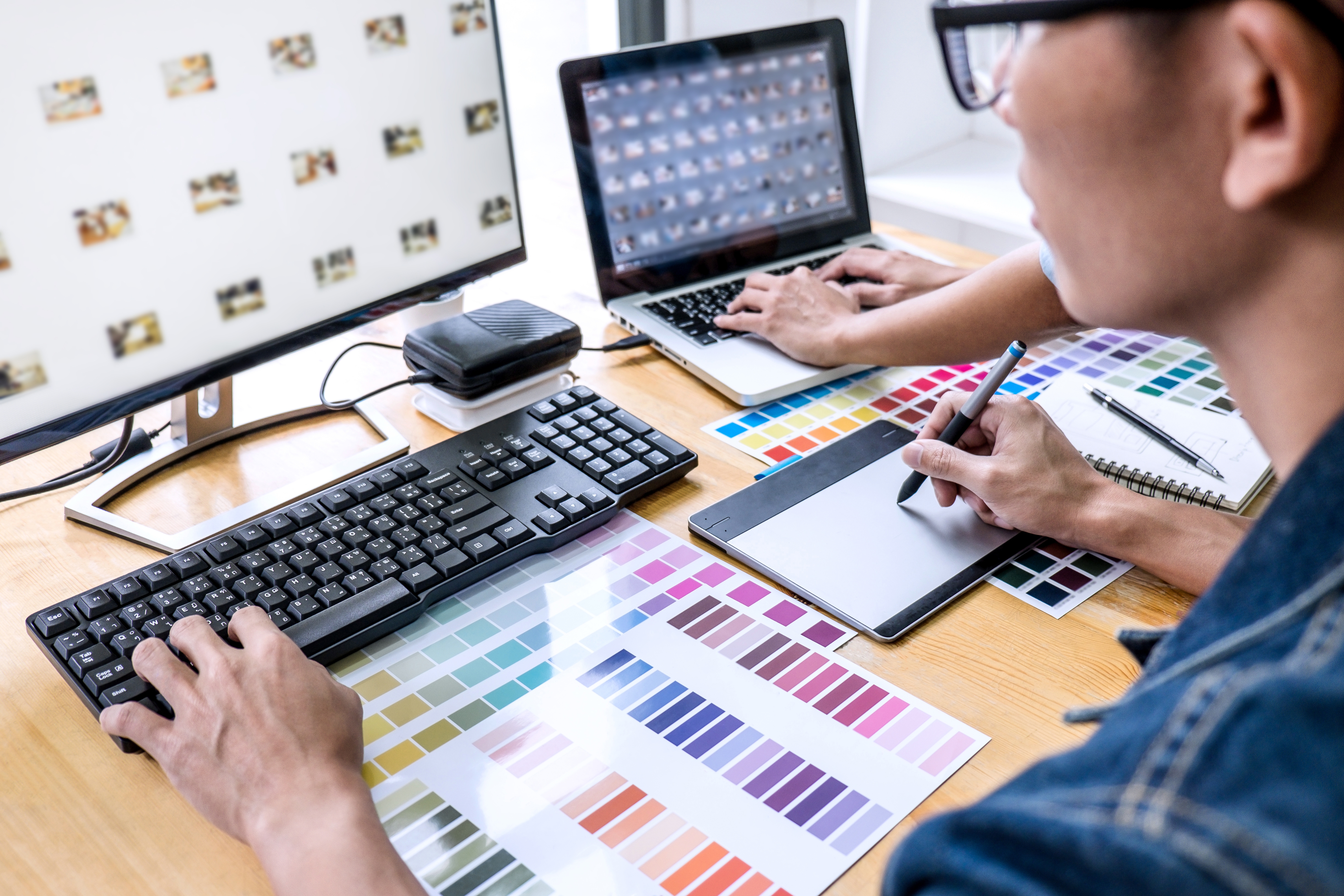 Team of young colleagues creative graphic designer working on color selection and drawing on graphics tablet at workplace, Color swatch samples chart for selection coloring.